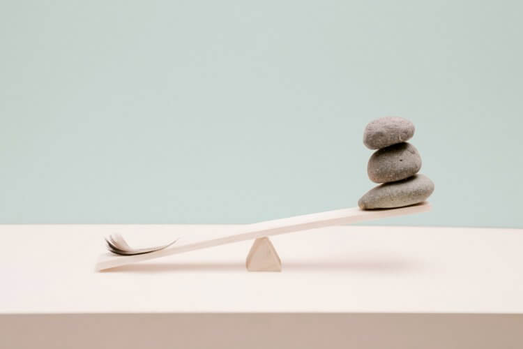 the header image for Slido's blog on team decision making depicting a wooden inclined plane with stones and feathers